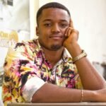 Young man wearing a colorful floral shirt, posing with a thoughtful expression indoors.