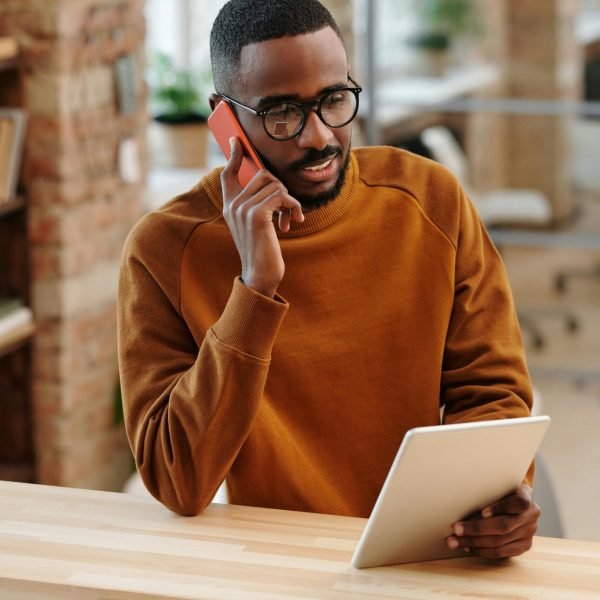 Young man in a modern office multitasking with a digital tablet and mobile phone.